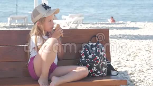 十几岁的女孩在暑假谈论坐在海边的长凳上吃冰淇淋孩子们在海滩上吃冰淇淋视频的预览图