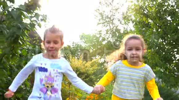 两个快乐漂亮的小女孩牵着手在新鲜空气中玩耍视频的预览图