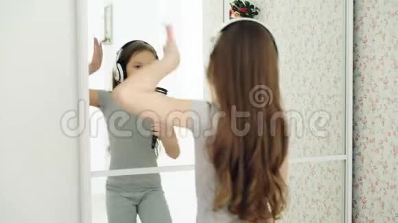美丽的小女孩在镜子前用梳子跳舞唱歌在家玩得开心视频的预览图