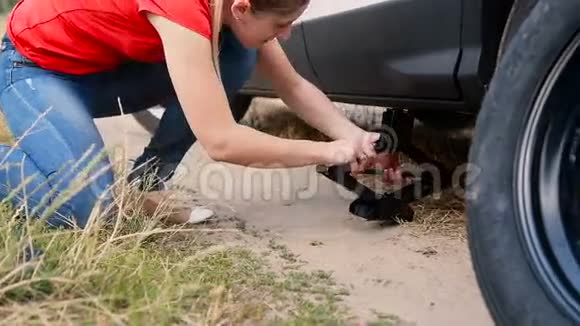 在农村土路上换轮胎前年轻女子用千斤顶把车抬起来视频的预览图