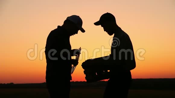 两个农民在日落时交谈在夕阳下看着番茄侧视图视频的预览图