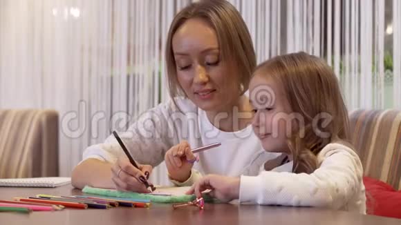 一位迷人的年轻女子妈妈和她可爱的小女儿画画视频的预览图