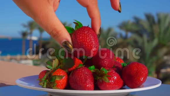 手从盘子里拿出一大块多汁的草莓视频的预览图