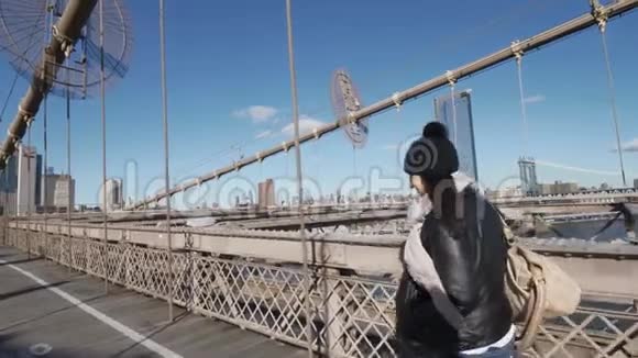 纽约的年轻女子在阳光明媚的一天走过布鲁克林大桥视频的预览图