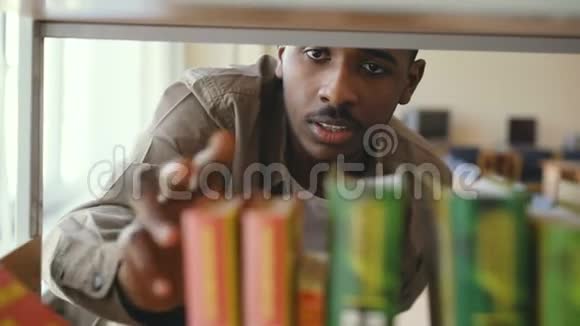 美国黑人严肃英俊的男学生正在大图书馆的书架上找课本拿了一本书视频的预览图