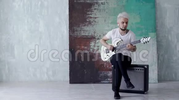 金发男人坐着弹吉他视频的预览图