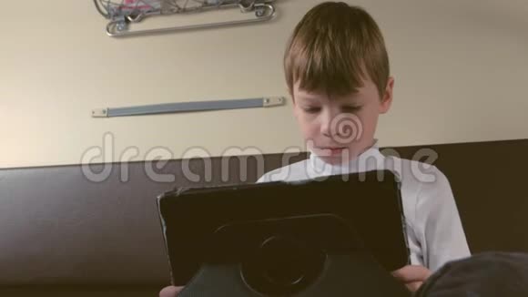 火车上的男孩正在二等车厢里玩平板电脑视频的预览图
