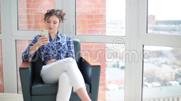 很高兴听到朋友的声音漂亮的年轻女人穿着优雅的衣服在智能手机上说话坐着微笑视频的预览图
