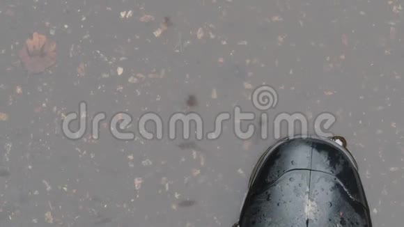 在水坑里穿着黑色橡胶靴的脚的俯视图视频的预览图