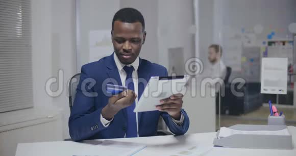 使用信用卡和平板电脑的非洲男性银行助理视频的预览图