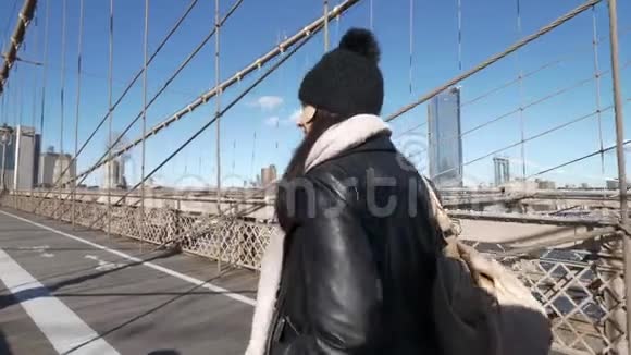 纽约的年轻女子在阳光明媚的一天走过布鲁克林大桥视频的预览图