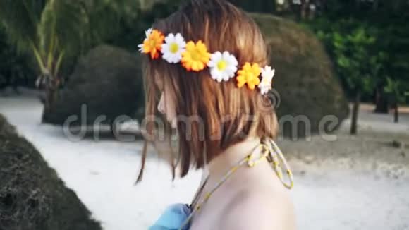 带着花环的女孩沿着海滩散步视频的预览图