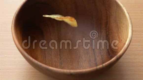 薯片掉进桌上的木碗里视频的预览图