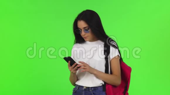带背包的迷人女学生带着智能手机自拍视频的预览图