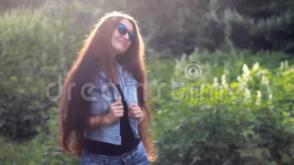美丽的女孩留着长长的头发戴着太阳镜在日落时享受着阳光明媚的夏日下午视频的预览图