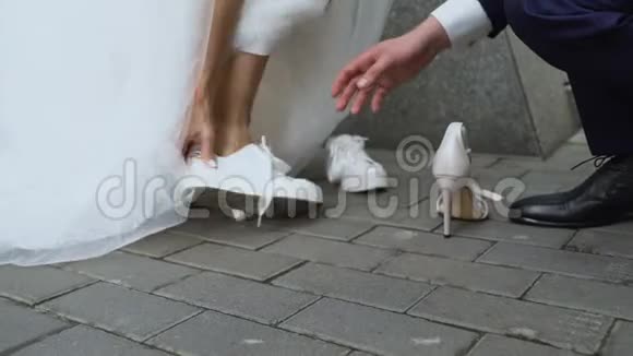 新郎帮助新娘穿着连衣裙凉鞋为活动穿舒适的鞋子护理视频的预览图