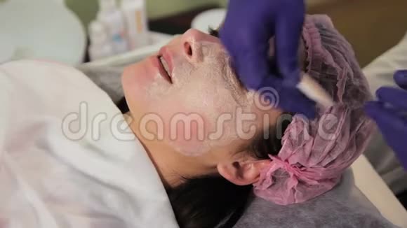 戴着手套的手从女人脸上摘下面具治疗后皮肤发红刺激特写视频的预览图