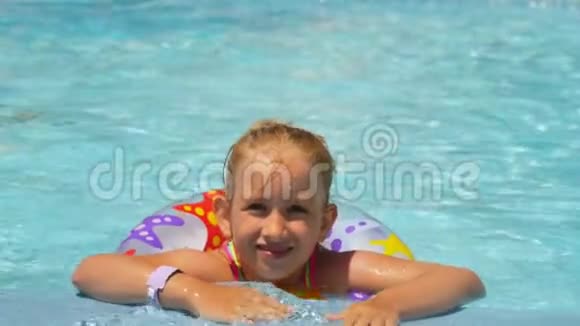 快乐的小女孩在炎热的夏天在户外游泳池里玩五颜六色的充气戒指孩子们学游泳视频的预览图