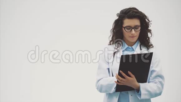 快乐的年轻女子医生在此期间持有带有文档的黑色文件夹有友好的表达方式去看看视频的预览图