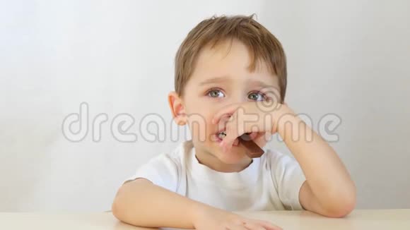 一个小男孩坐在白色背景的桌子旁吃巧克力视频的预览图