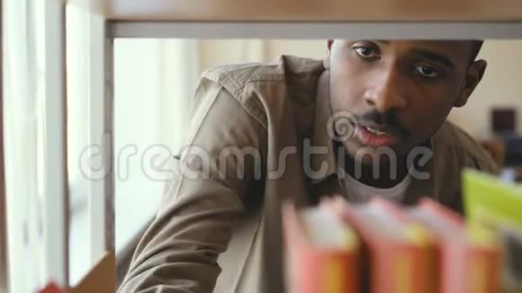 非裔美国人英俊的男学生正在大学图书馆的书架上寻找教科书他找到了书视频的预览图