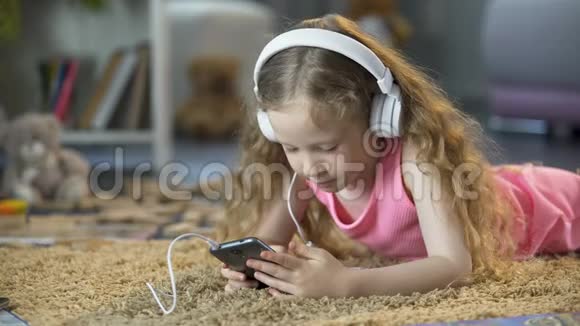 可爱的女孩专注于智能手机上的虚拟游戏和音乐应用程序视频的预览图