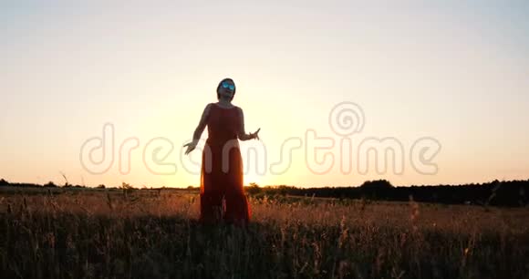 美丽的中年妇女在夕阳下的田野里慢悠悠地跳舞视频的预览图