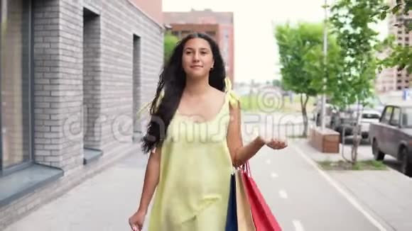 穿着长裙的年轻女孩购物后心情愉快地环游城市4K视频的预览图