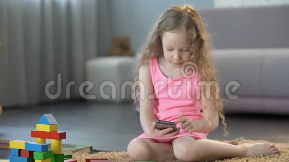 小女孩忽视玩具在手机应用程序中玩游戏沉迷于智能手机视频的预览图