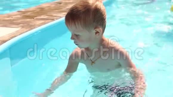 一个有趣的金发男孩在夏天在游泳池里玩和游泳视频的预览图