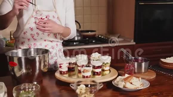 一位女士在厨房准备甜点一位女士在玻璃杯中涂抹奶油视频的预览图