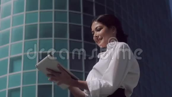 微笑的商务女性站在户外阳光明媚的一天在她的平板电脑上工作视频的预览图