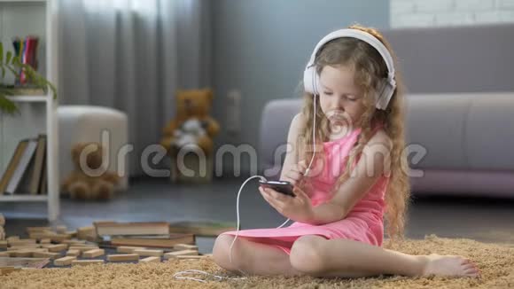 戴着耳机的孩子在智能手机上听音乐沉迷于科技视频的预览图