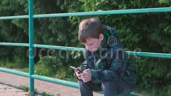 男孩打电话坐在公园里说话视频的预览图