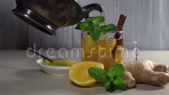 把茶壶里的茶倒入一个装有柠檬肉桂和薄荷的杯子里视频的预览图