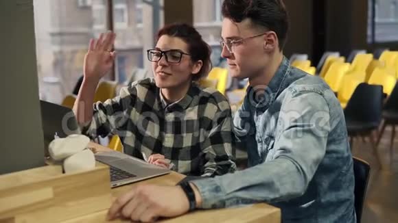 两个戴着眼镜的年轻人坐在一起通过视频聊天与某人交谈视频的预览图