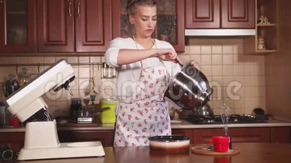 年轻女子在家里的厨房里做蛋糕她用奶油做蛋糕视频的预览图