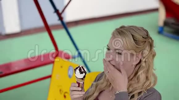 年轻可爱的金发女孩在秋千上吃冰淇淋视频的预览图