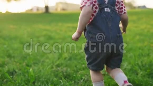 日落时一个孩子在草地上奔跑的腿视频的预览图