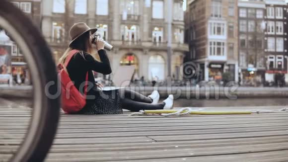 4年轻的创意女孩坐在外面的笔记本电脑时尚艺术博主在户外工作自由斯坦迪卡姆的生活方式拍摄视频的预览图