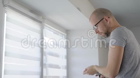 一个成年男子手里拿着电钻用螺丝把窗户拧下来保护他不受光线照射视频的预览图