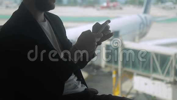 商人正在机场的智能手机屏幕上打字视频的预览图