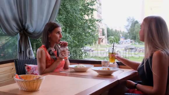 两个长发女孩正在一家咖啡馆里休息里面有一个现代的内部和笑声室内滑稽微笑女士画像视频的预览图