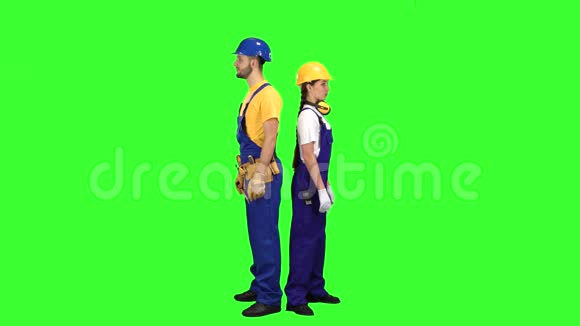 有女建筑工人的家伙背靠背站着指着他们的朋友绿色屏幕视频的预览图