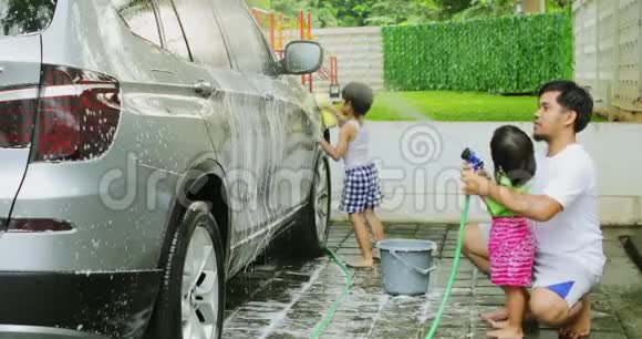 两个快乐的孩子和他们的父亲在洗车视频的预览图