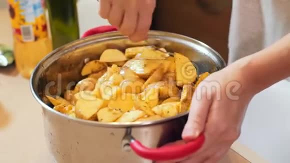 特写女性手将土豆混合在锅里视频的预览图