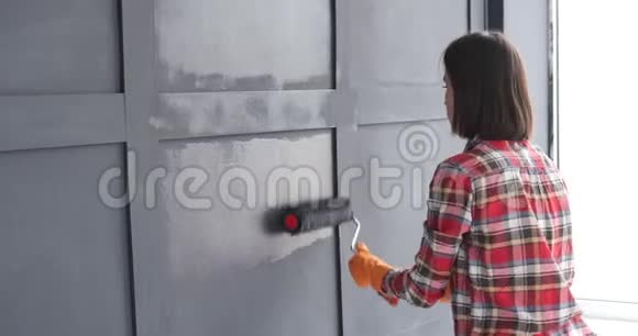 女人用滚筒画木墙视频的预览图