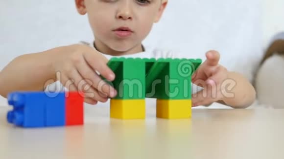 一个孩子在玩彩色积木坐在白色背景上的桌子旁动作缓慢特写儿童和儿童视频的预览图