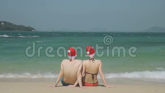 可爱的一对夫妇坐在海边的沙滩上望着美丽的景色视频的预览图