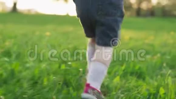 日落时一个孩子在草地上奔跑的腿视频的预览图